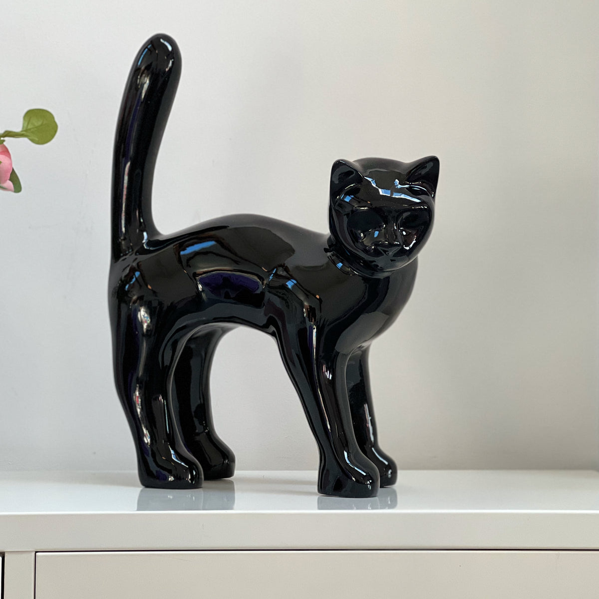 El Gato — Negro Tinta sobre un aparador en casa, foto real, 45 cm