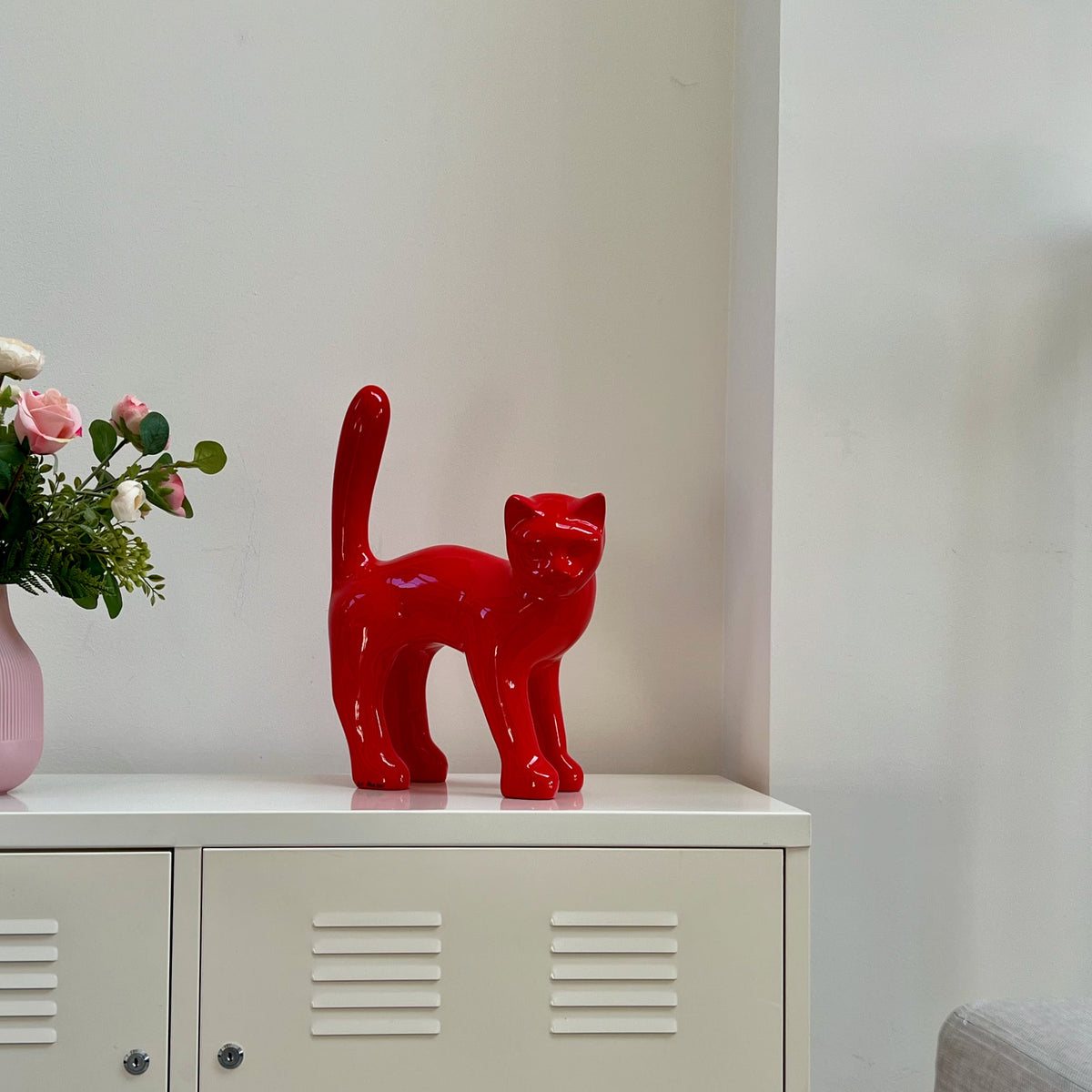The Cat — Signal Red next to a vase of roses, showing its real size